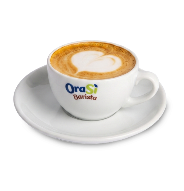 Biała filiżanka do cappuccino z latte art w kształcie serca, etykieta "OraSì Barista", na spodku, białe tło