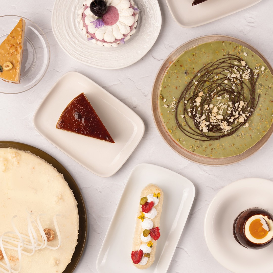 Widok z góry na desery: sernik, flan, tarta pistacjowa, eklerka i pucharki z mus czekoladowym
