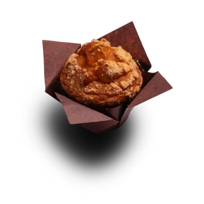 Złoty muffin z kruszonką streusel i nadzieniem owocowym, w brązowej papilotce, na białym tle.