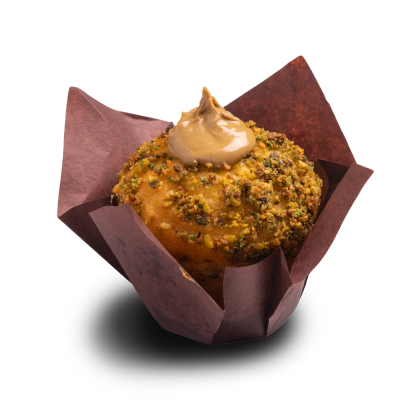 Muffin obtoczony w posiekanych pistacjach, z wirem lukru karmelowego, w brązowej papilotce tulipan.