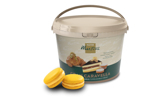 Beżowe wiaderko kremu do smarowania Master Martini Gran Caravella obok dwóch żółtych macarons i nadzianego wypieku.