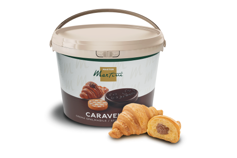 Beżowe wiadro kremu czekoladowego Caravel Master Martini obok dwóch croissantów, jeden z czekoladowym nadzieniem.